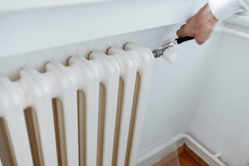 Plumber fixing radiator with wrench. Hands with adjustable wrench repairs a heating radiator....