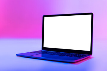 Fototapeta premium Modern laptop pc with empty white screen in neon light, space for website or desktop. Mockup