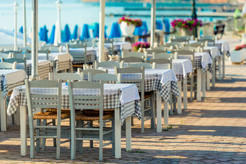 Range of wooden table and white chair for relaxation at restaurant near sea