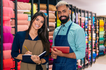 portrait of sales team looking at camera and smiling with notebook at fabric store