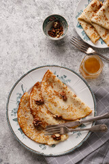 Homemade pancakes with nuts and honey on a gray textured background