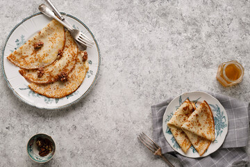 Homemade pancakes with nuts and honey on a gray textured background