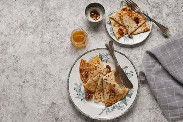 Homemade pancakes with nuts and honey on a gray textured background
