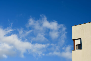 Clouds in the blue sky with a building with a window next to it
