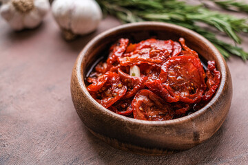 Sun dried tomatoes  in wooden bowl. Dried tomatoes with olive oil, rosemary, salt, herbs and garlic recipe.  Dark background. 