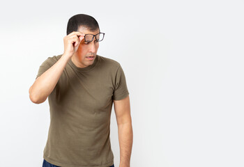 Waist up portrait of man with glasses taking them off to look at empty space aside isolated white background