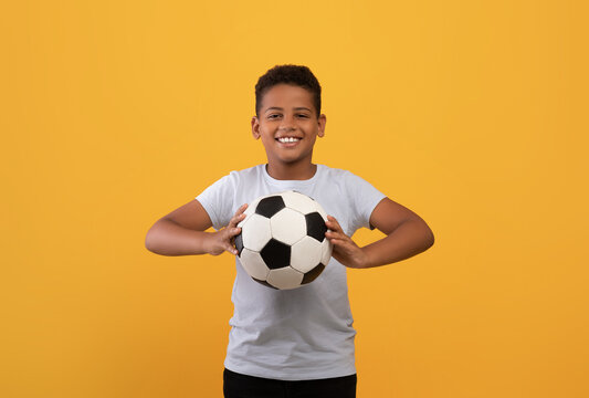 Cheerful black school boy holding soccer ball
