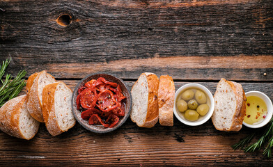 Italian ingredients  food background. Slices of ciabatta bread  on wooden board with olives, dried...