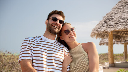 travel, tourism and people concept - happy couple in sunglasses over tropical beach background in...