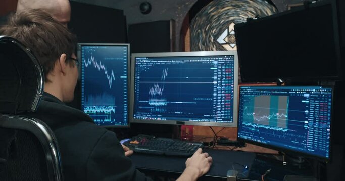 Two male traders on stock exchange, discussing charts of falling and rising quotes on the monitor screen, home environment, freelance. Concept of playing on stock, futures and bonds trading exchange