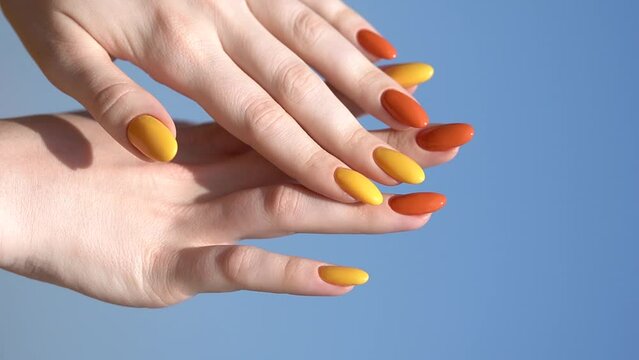 Hands of a young woman with a bright beautiful manicure against the sky