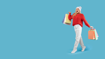 Excited blonde woman walking with shopping bags at studio