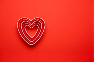 Сolorful cutters cookies in heart shape on red background. Concept Valentine's card. Top view Copy space for text.
