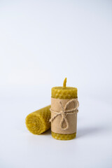two wax candles wrapped in kraft paper and tied with twine on a white background. natural beeswax. handmade candles