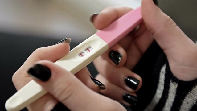 Positive pregnancy test in the hands of a teenage girl.