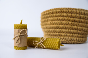 composition of two wax candles and a knitted basket made of jute on a white background. handmade from natural materials