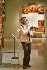 Woman visitor holds a booklet with an exhibition program the museum.