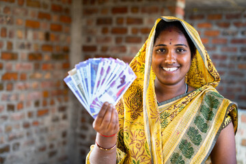 Happy smiling Indian woman with currency notes looking at camera - concept of daily wager or...