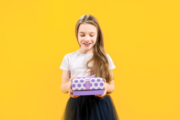 Congratulations. Gift wrap. A cute girl delighted in a white t-shirt and black skirt holds a gift in her hands. Happy birthday birthday girl.