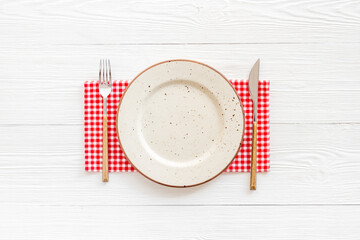 White plate with fork and knife on table napkin. Table setting
