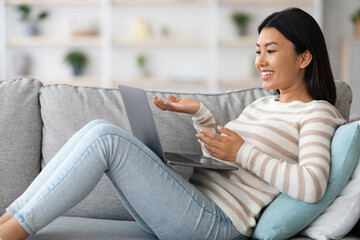 Obraz premium Positive Young Asian Female Using Laptop For Video Call At Home