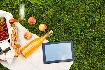 leisure, technology and summer concept - close up of tablet pc computer, picnic basket and bottle...