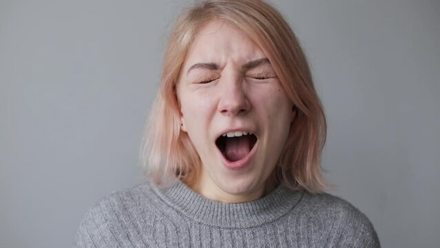 Portrait of a young tired woman looking at the camera and yawning