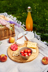 leisure and drinks concept - close up of food, drinks and basket on picnic blanket on grass