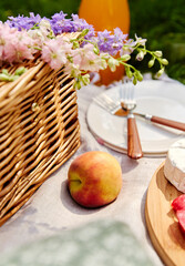 leisure and drinks concept - close up of food, drinks and basket on picnic blanket on grass