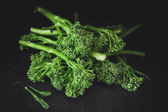 Fresh bimi vegetable on a dark table. A heap of raw baby broccoli.