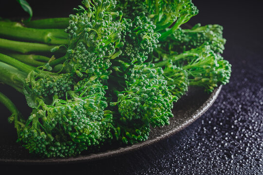 Fresh bimi vegetable on a dark table. Raw baby broccoli. Closeup of raw baby broccoli with water droplets.