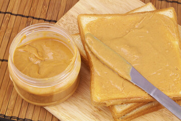 Peanut butter spread with table knife and bread