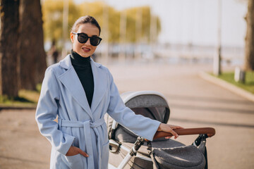 Young asian woman mother, walking with baby stroller in park