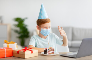 Boy in face mask and festive cap celebrating birthday