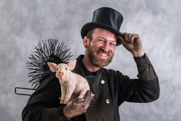 Schornsteinfeger in Berufskleidung hält Glücksschwein in der Hand und grüßt mit seinem Zylinder.