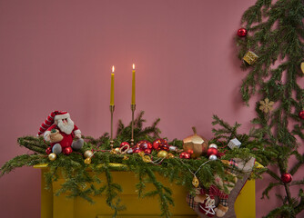 Close up fireplace with pine branch decoration, pink wall background with candle and gift box style.