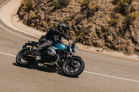 Almeria, Spain - May 5th 2021: Man riding a BMW R NineT Pure motorcycle in a mountain road across beautiful turns, during Dunlop Xperience event in Almeria mountain range, Spain.