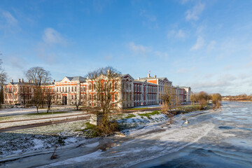 Fototapeta na wymiar View to Jelgava Palace or historically Mitau Place built in the 18th century and ice covered river Lielupe from traffic bridge. Baroque-style university, museum, residence in Jelgava.