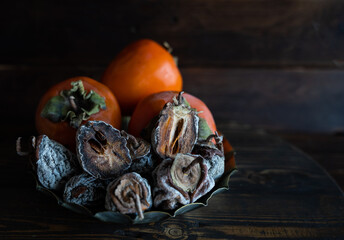 Dried persimmon and fresh persimmon on a wooden background. Healthy diet. Healthy diet