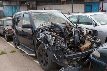 crashed black crossover,  sport utility vehicle car after frontal collision accident with broken...