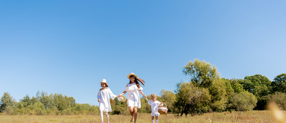 Sisters walk across the field, holding hands. Time with family. Cheerful picnic in the park