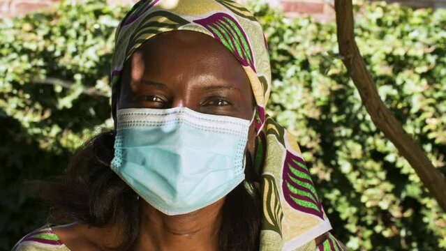 Middle Aged African Woman Outside Wearing Traditional Clothes And A Face Mask During COVID-19 Coronavirus Pandemic In Africa