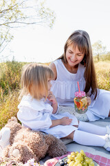 Summer family picnic in the shade of a tree. Mom and daughter are relaxing in nature.