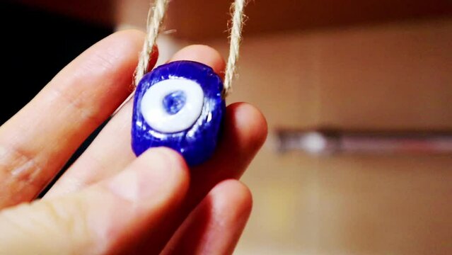 Cheshm nazar boncugu. In Turkic countries amulet against evil is also known as the evil eye. Blue glass amulet in woman's hand. Charm at home for protection from trouble. Symbol of good luck happiness