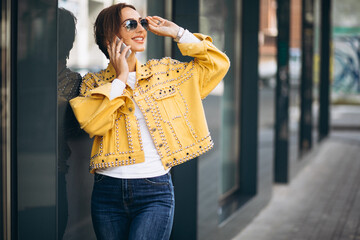 Young woman in yellow jacket using phone outside in the street