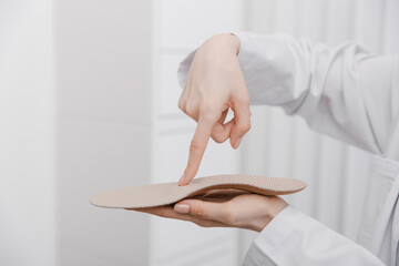 Doctor holding orthopedic insoles in his hands. Orthopedist tests the medical device. Orthopedic insoles on a white. Foot care. Flat Feet Correction. Prevention of flat feet and foot diseases
