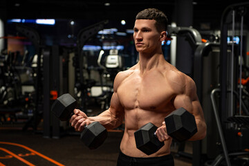 Shirtless man doing tricep curls with dumbbells in gym, triceps workout