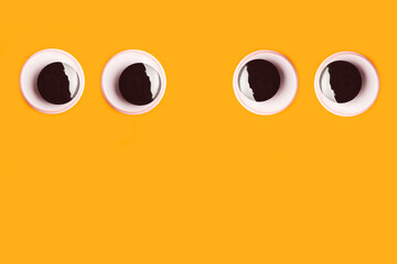 Fototapeta premium Dos pares de ojos grandes de juguete saltones mirandose entre si sobre un fondo anaranjado liso y aislado. Vista de frente y de cerca. Copy space