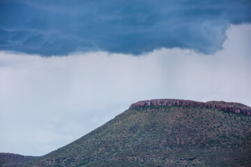 I hilltop in the Karoo in South Africa with an overhanging storm cloud