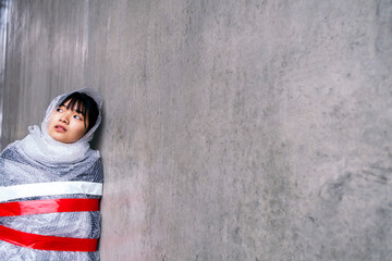 Thoughtful woman wrapped in bubble wrap leaning on wall